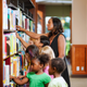 Diverse preschool children with teacher exploring books in the library