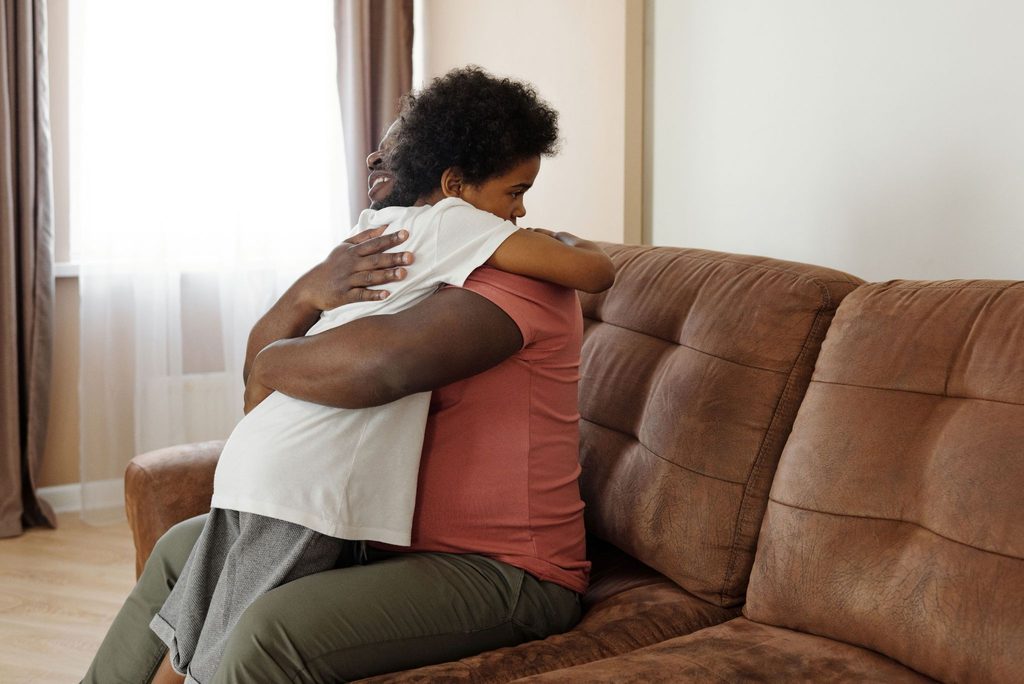 A father giving his child a reassuring hug while sitting on a couch