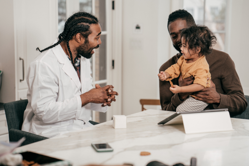 A father holding his son while talking to a Pediatrician