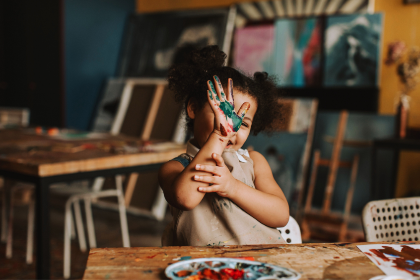 Joyful child showing painted hands in a vibrant art studio setting