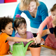 Diverse preschool children planting a seed together with their teacher
